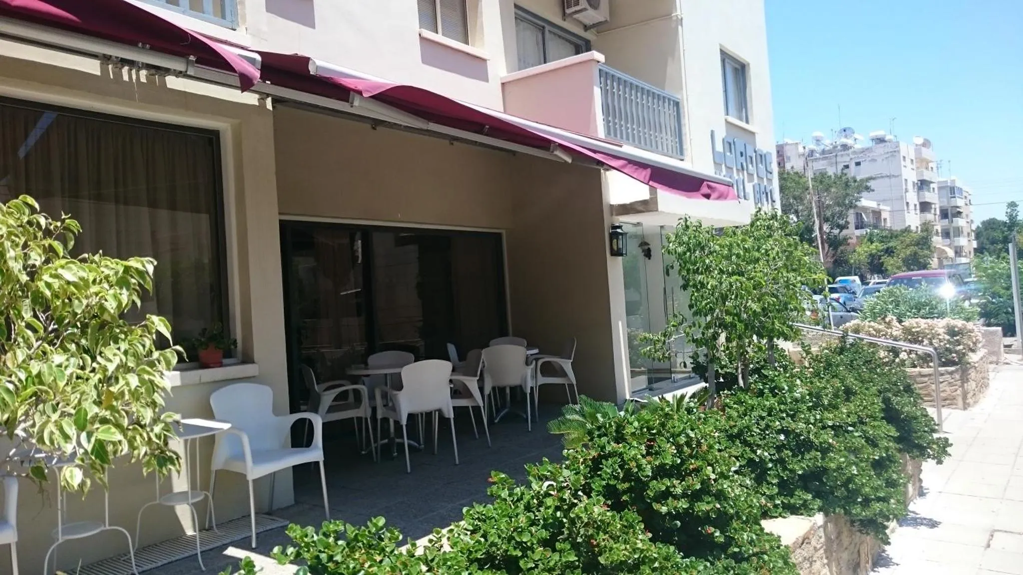 Terrasse ombragée avec tables et chaises devant un bâtiment.