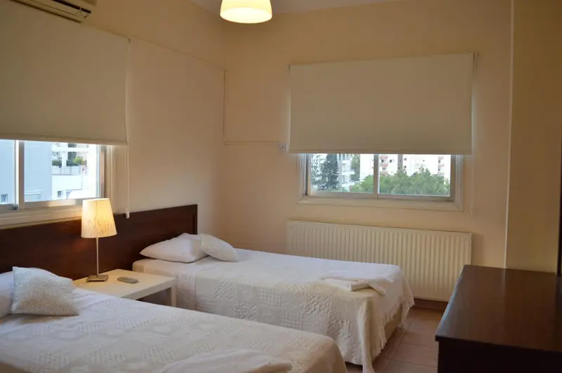 Chambre lumineuse avec deux lits simples et une vue sur la ville.