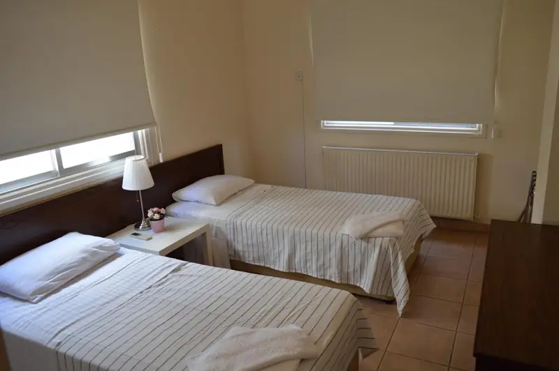 Une chambre lumineuse avec deux lits simples et une décoration sobre.