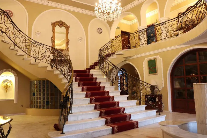 Un escalier en marbre rouge et blanc orne un hall spacieux et lumineux.