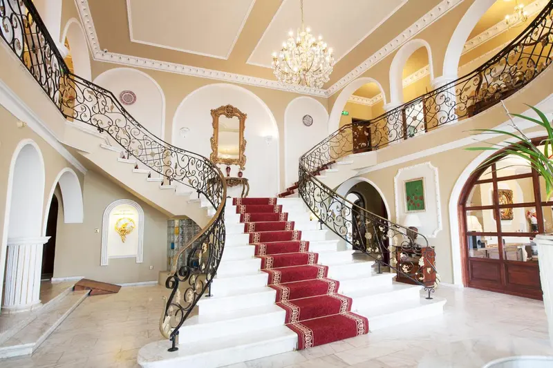 Un escalier rouge et blanc orné de fer forgé s'élève dans un hall spacieux et lumineux.