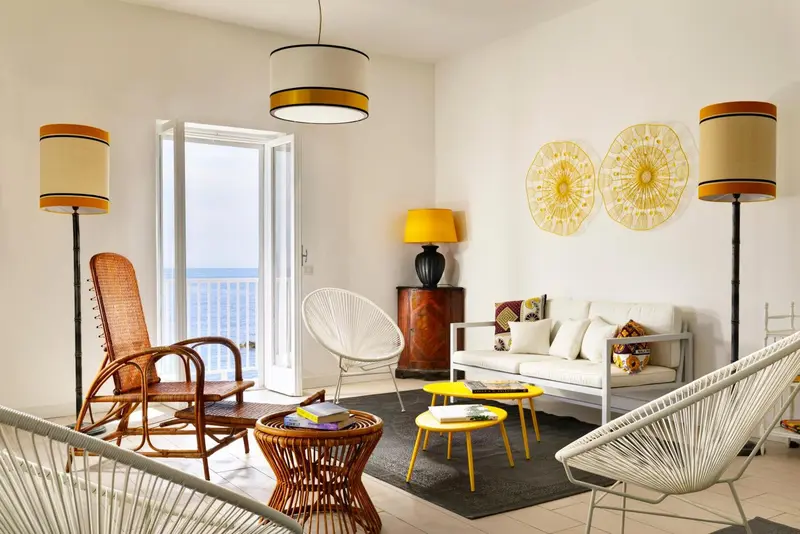 Un salon lumineux avec des fauteuils en rotin et une vue sur la mer.