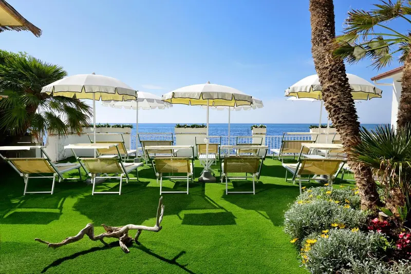Terrasse avec transats et parasols face à la mer.