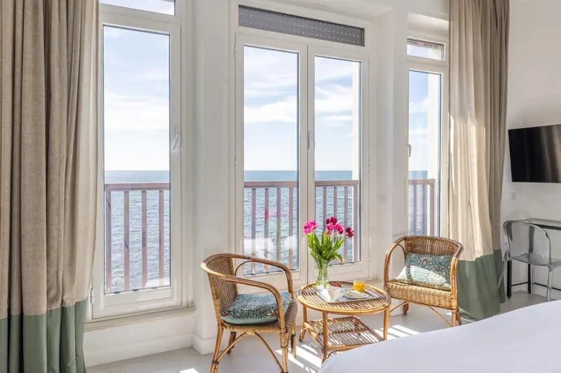 Une pièce lumineuse avec deux fauteuils et une vue sur la mer.