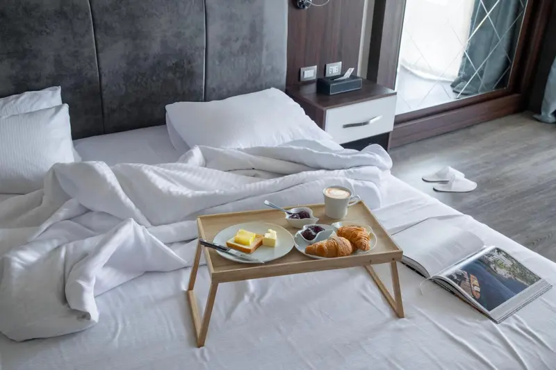 Un petit-déjeuner est servi sur un lit défait dans une chambre d'hôtel.