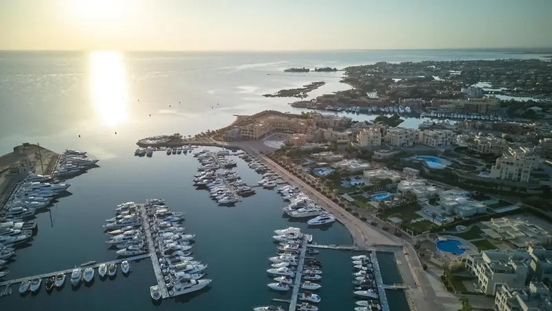 Vue aérienne d'une marina bordée de bâtiments et de plages.