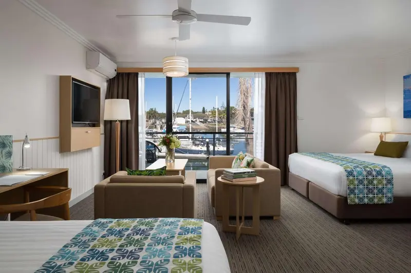 Une chambre lumineuse avec un coin salon et vue sur un port de plaisance.