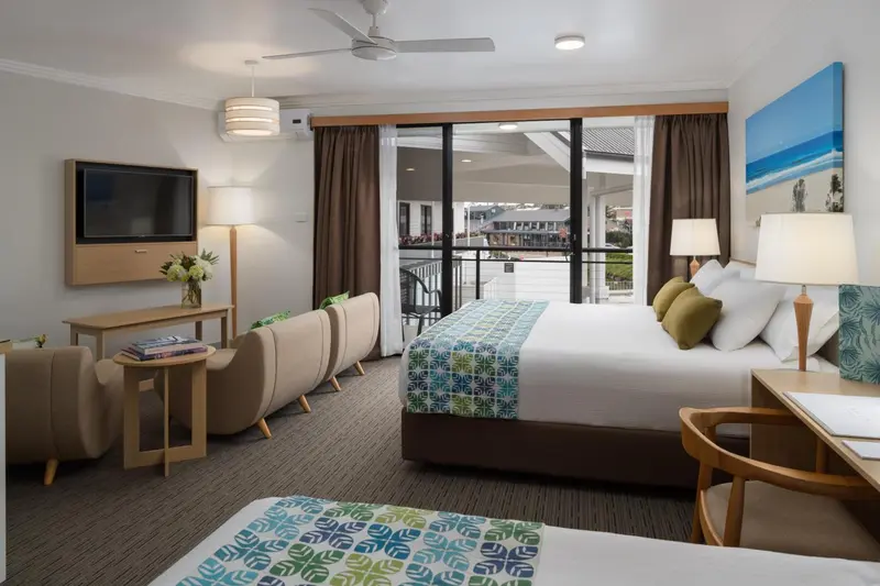 Une chambre d'hôtel lumineuse avec un lit double et un coin salon.