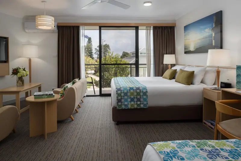 Une chambre lumineuse avec un grand lit et un coin salon.