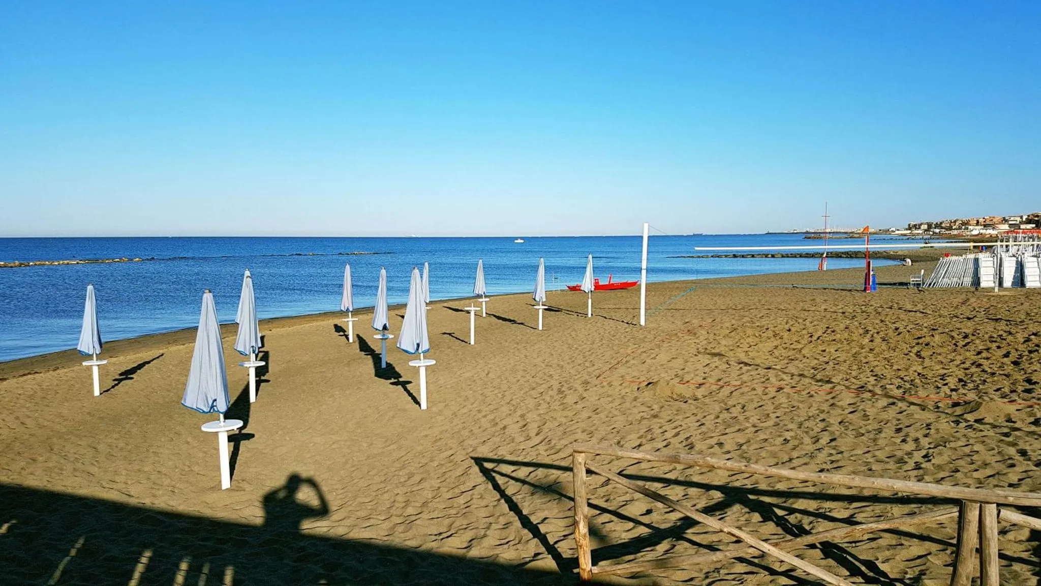 Plage de sable avec parasols et vue sur la mer.