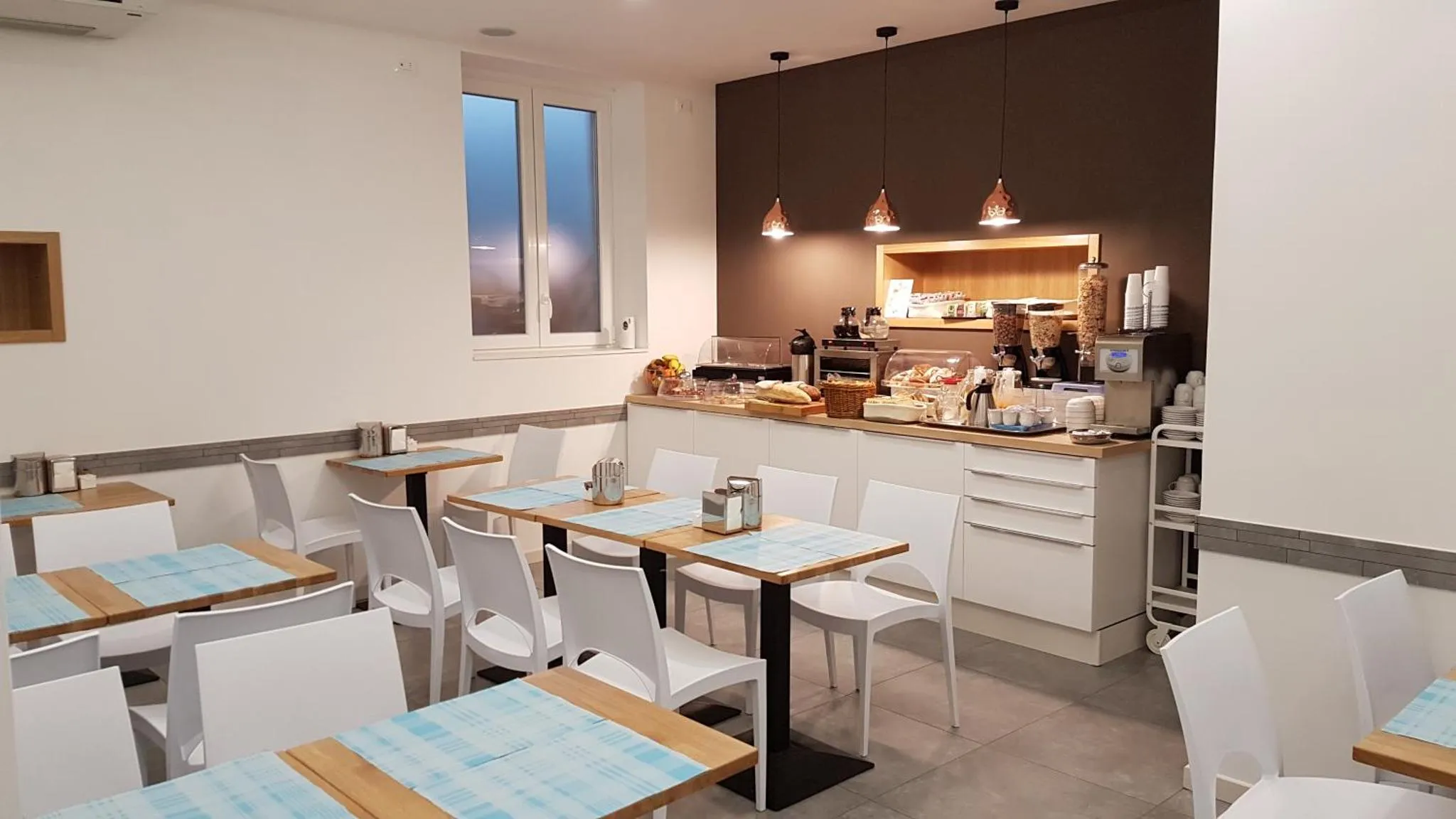 Une salle lumineuse avec des tables et des chaises, un comptoir de buffet et une fenêtre.