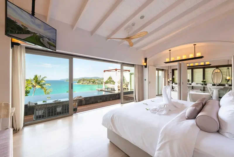Une chambre lumineuse avec un grand lit donnant sur une vue mer.