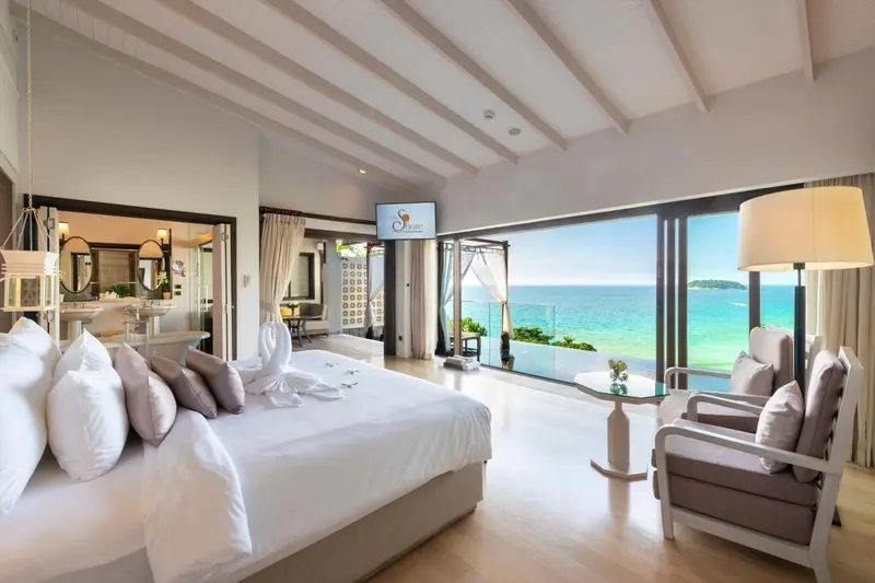 Une chambre lumineuse avec un grand lit donnant sur une vue mer.