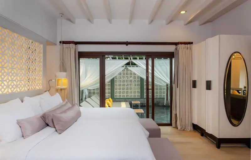 Une chambre lumineuse avec un grand lit et un accès à une terrasse.