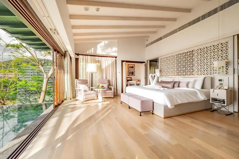 Une chambre lumineuse avec un grand lit et un coin salon donnant sur une terrasse.