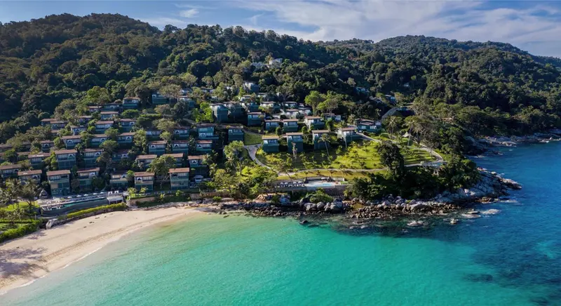 Vue aérienne d'un complexe hôtelier sur une côte rocheuse et une plage de sable fin.