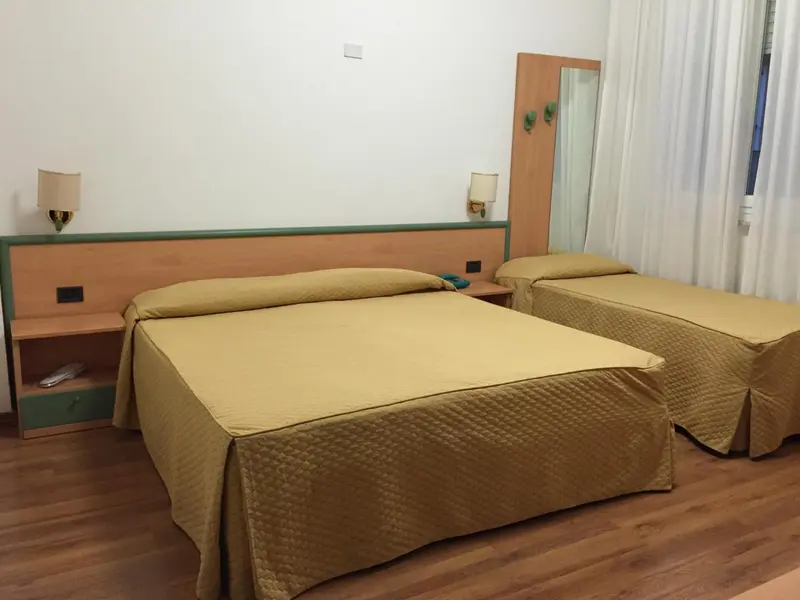 Une chambre d'hôtel avec deux lits simples recouverts d'une courtepointe jaune.
