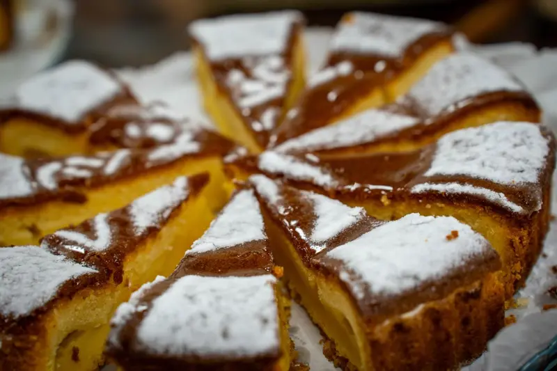 Une tarte au chocolat saupoudrée de sucre glace est présentée en parts.
