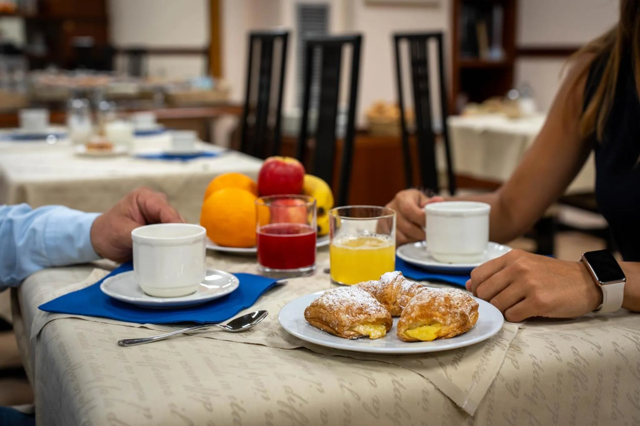 Une table est dressée pour le petit-déjeuner avec des viennoiseries et des boissons.