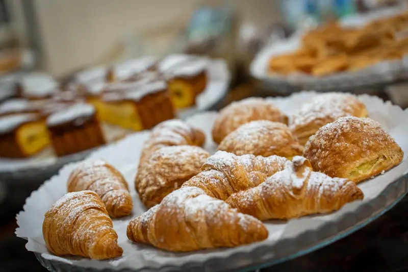 Assortiment de viennoiseries et de pâtisseries présentées sur des plateaux.