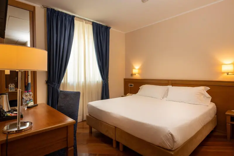 Une chambre d'hôtel lumineuse avec un lit double et un bureau.