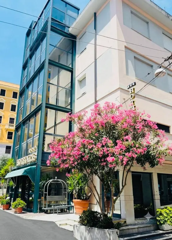 Façade d'un bâtiment avec un arbuste en fleurs devant l'entrée.