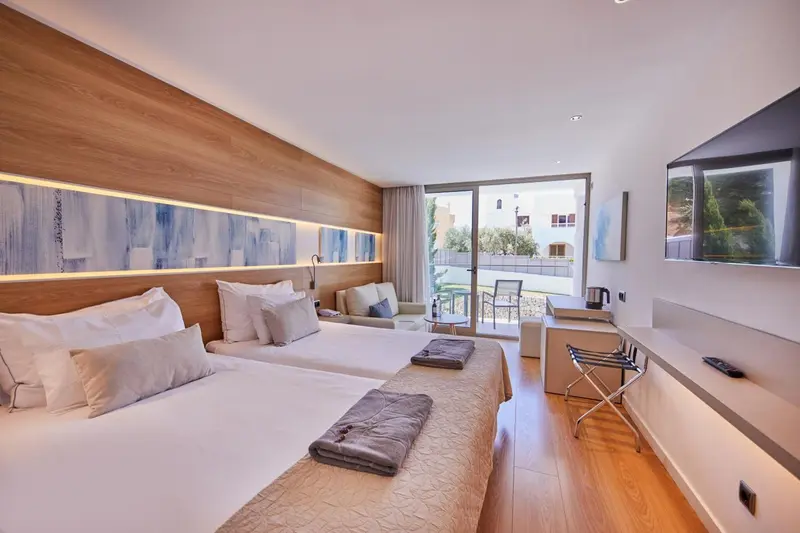 Chambre lumineuse avec un grand lit et un accès à une terrasse.