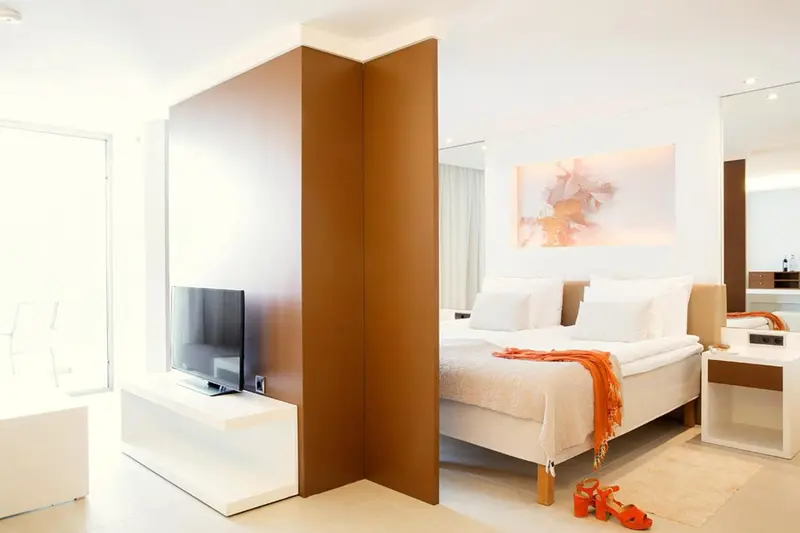 Une chambre lumineuse avec un grand lit et une télévision à écran plat.