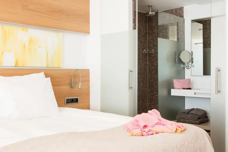 Une chambre lumineuse avec un grand lit et une salle de bain moderne.