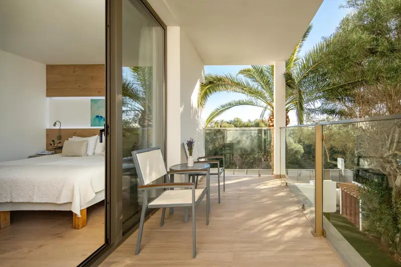 Une chambre lumineuse s'ouvre sur une terrasse avec mobilier.