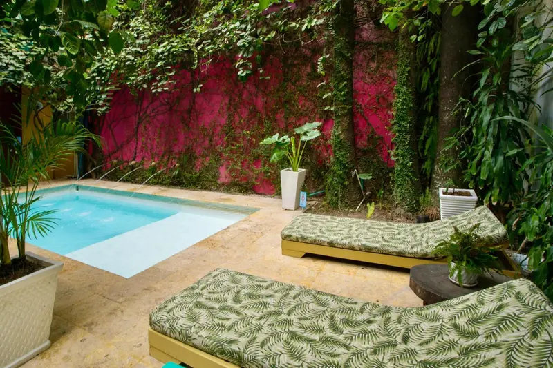 Petite piscine rectangulaire entourée d'un espace de détente avec des transats.