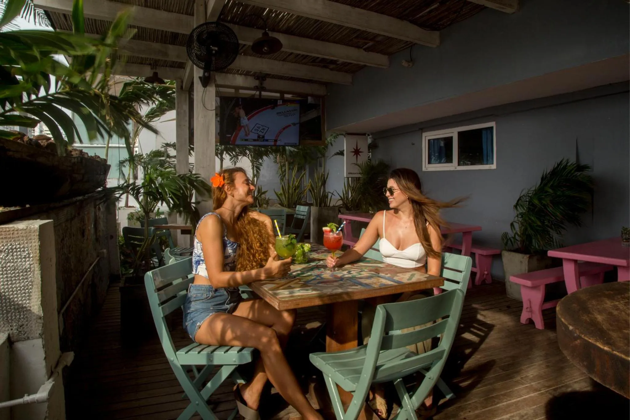 Deux femmes assises à une table de bar en extérieur, profitant de leurs boissons.