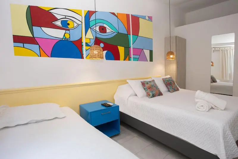 Chambre lumineuse avec deux lits et décoration murale colorée.
