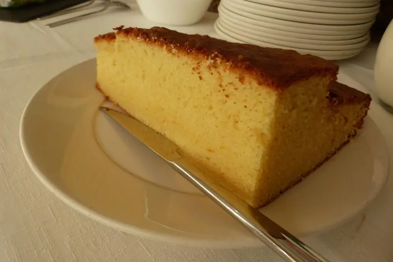 Une part de gâteau est présentée sur une assiette blanche avec un couteau.