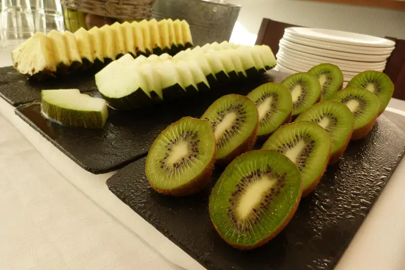Assortiment de fruits frais coupés, dont du melon, du kiwi et de la pastèque, présentés sur des ardoises.