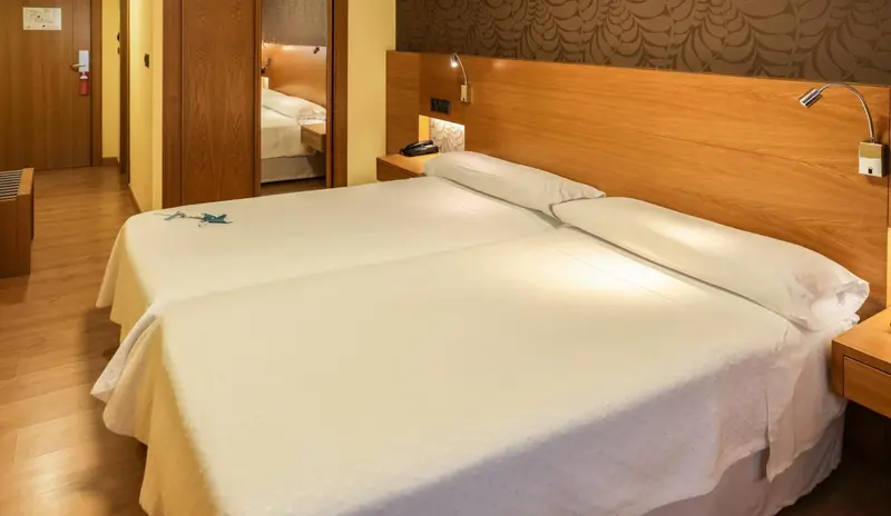Une chambre lumineuse avec un grand lit recouvert de draps blancs.