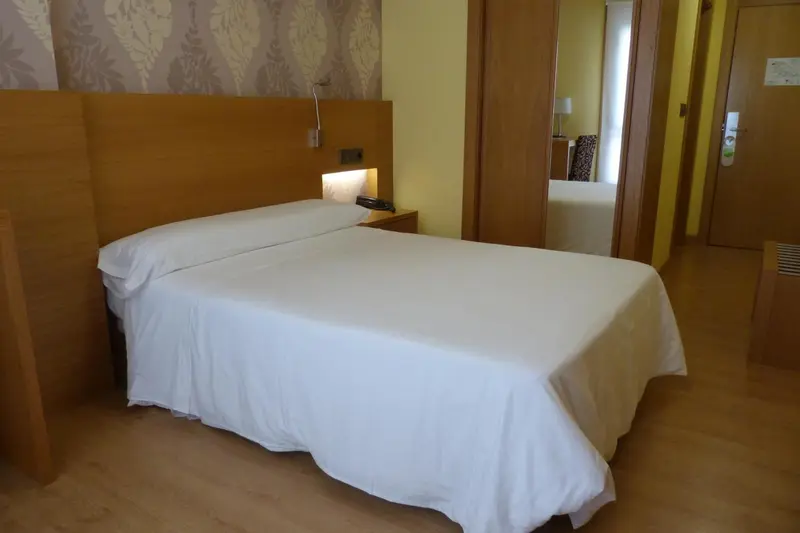 Une chambre lumineuse avec un grand lit recouvert de draps blancs.