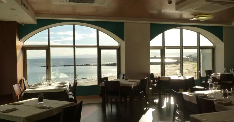 Une salle à manger lumineuse offre une vue dégagée sur la mer.