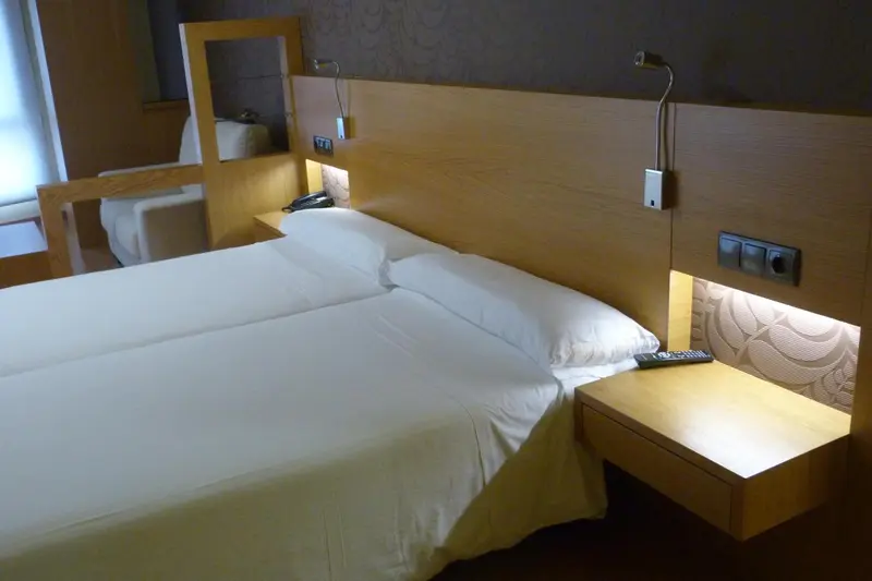 Une chambre avec un grand lit recouvert d'une couette blanche et des tables de chevet en bois.