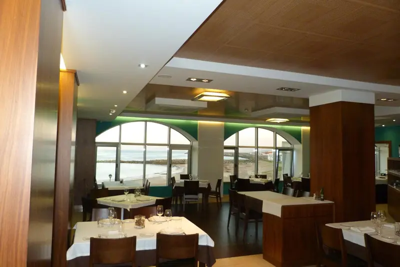 Une salle de restaurant lumineuse avec de grandes fenêtres donnant sur la mer.