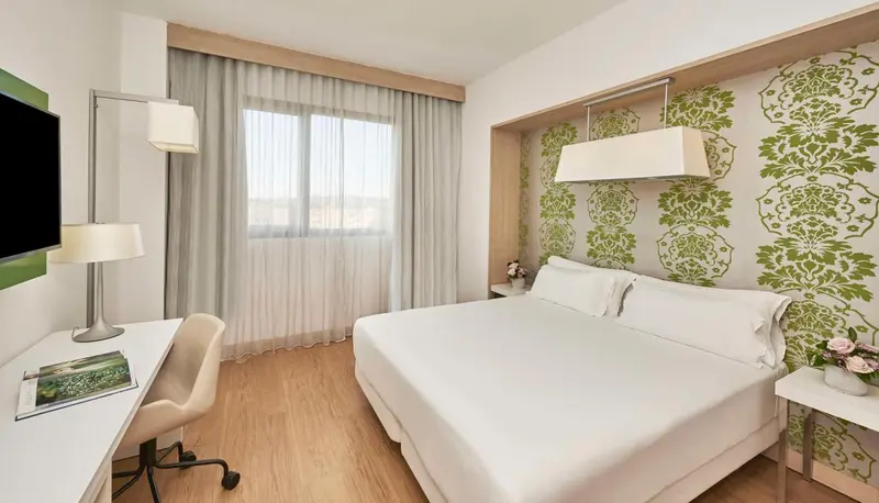 Une chambre lumineuse avec un grand lit et un bureau.