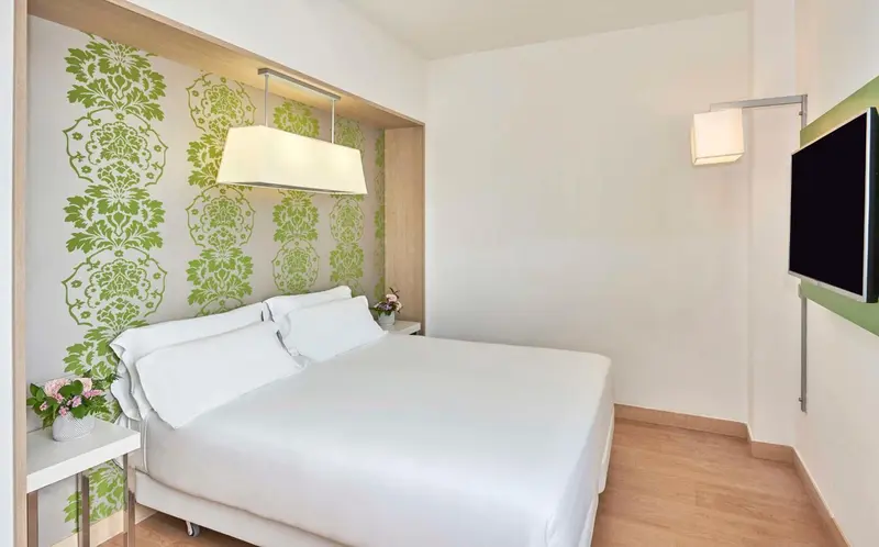 Une chambre lumineuse avec un grand lit blanc et une décoration florale.