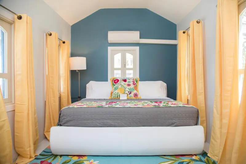 Une chambre lumineuse avec un grand lit recouvert d'une couette colorée.