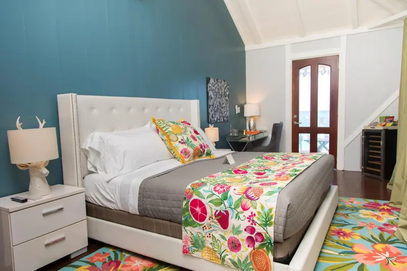 Une chambre lumineuse avec un grand lit recouvert d'une courtepointe colorée.