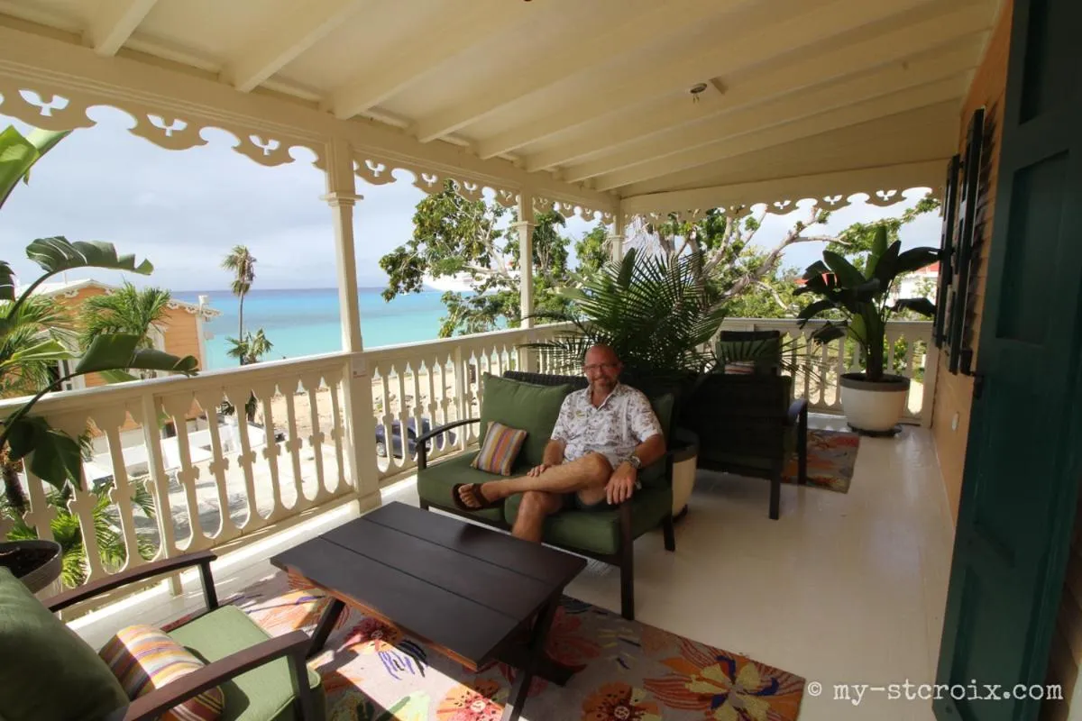 Un homme est assis sur des fauteuils sur une terrasse avec vue sur la mer.