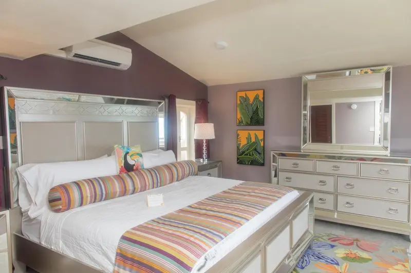 Une chambre colorée avec un grand lit et des tableaux tropicaux.