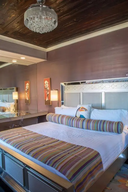 Une chambre avec un grand lit recouvert d'une courtepointe colorée et décorée de coussins.