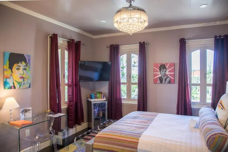 Une chambre lumineuse avec un lit recouvert d'une courtepointe colorée et des œuvres d'art murales.