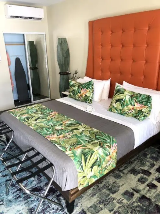 Une chambre avec un grand lit recouvert d'une courtepointe à motifs végétaux et d'oreillers décoratifs.