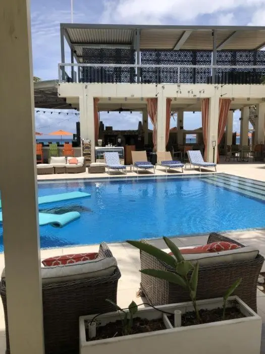 Une piscine turquoise bordée de chaises longues et de végétation luxuriante.